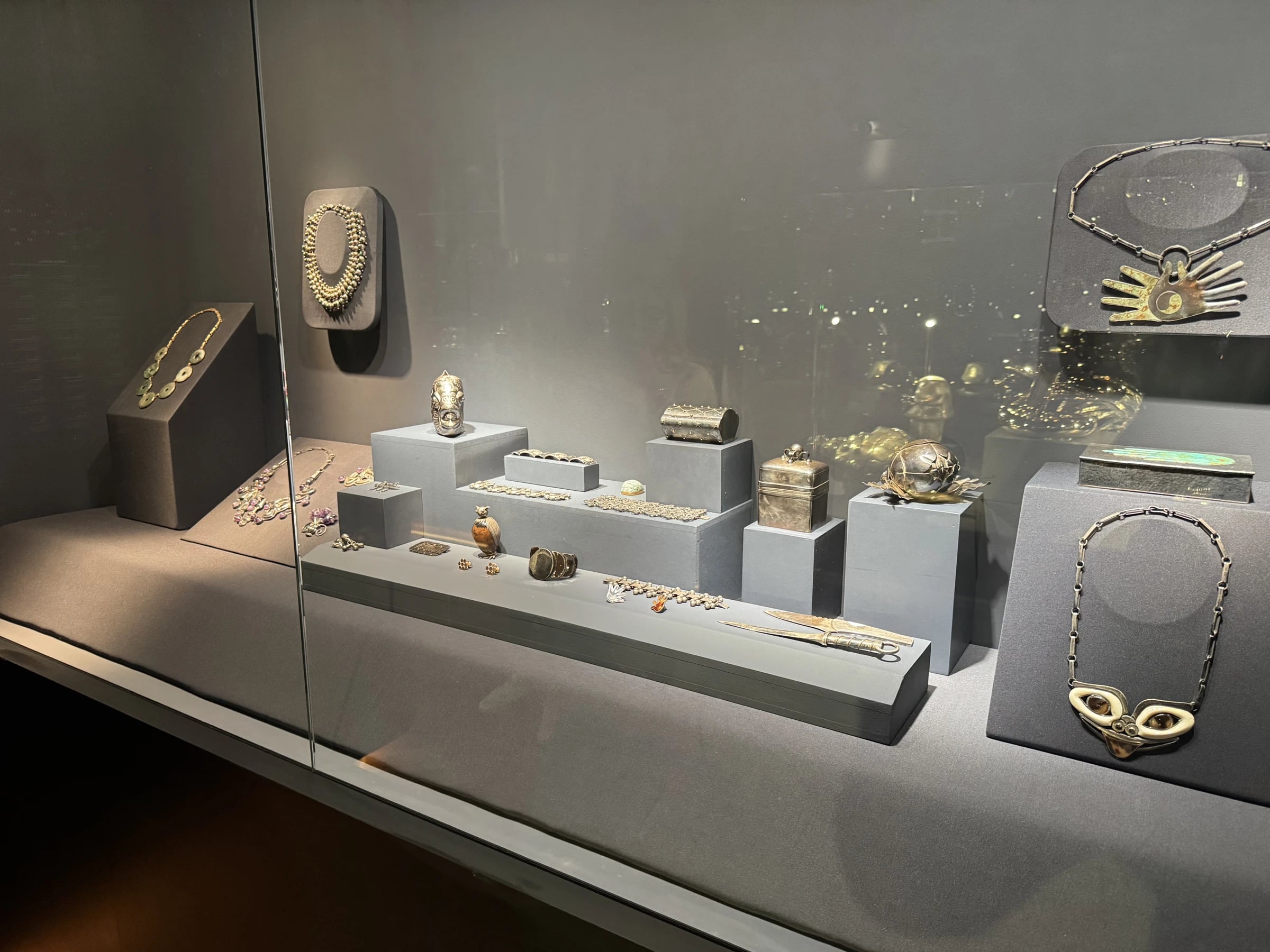 Jewelry case view, second angle: mask necklace, hands necklace, cases and small silver