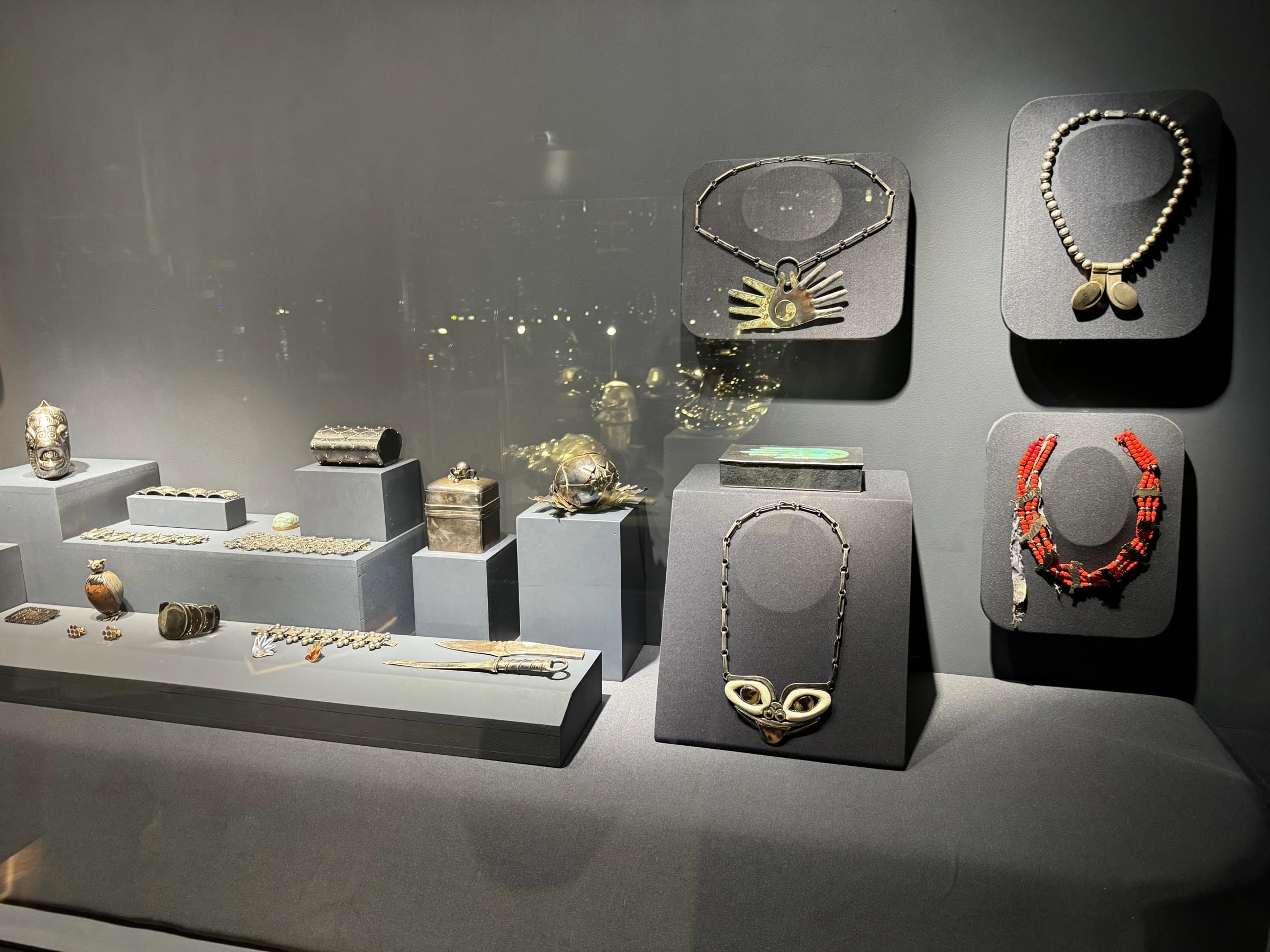 Jewelry case view: hands necklace, mask necklace, bead and coral necklaces, boxes