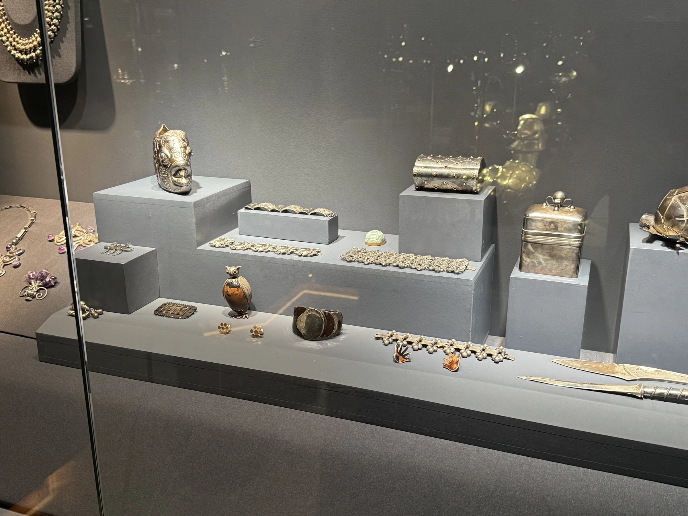 Case view: owl figure, caskets, bracelets, mask head, brooches